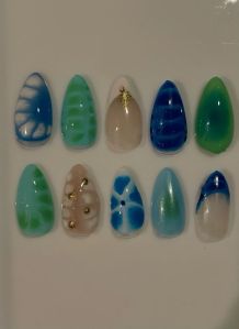 Close-up of blue and green aura nails with gold accents