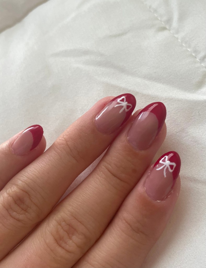 Red French tip nails with a white bow accent on select nails, combining bold elegance with a playful touch.